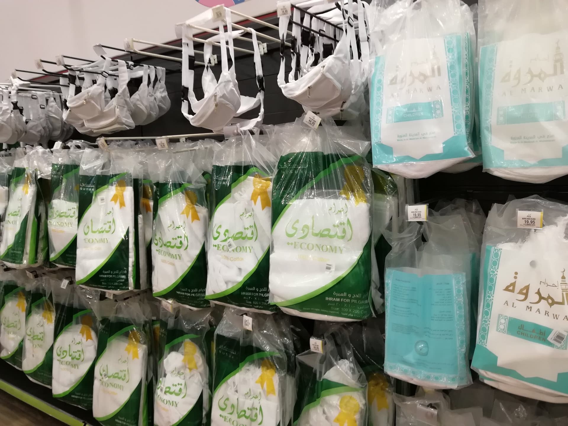 Bir mağazada paketler hâlinde asılı duran beyaz ihram takımları